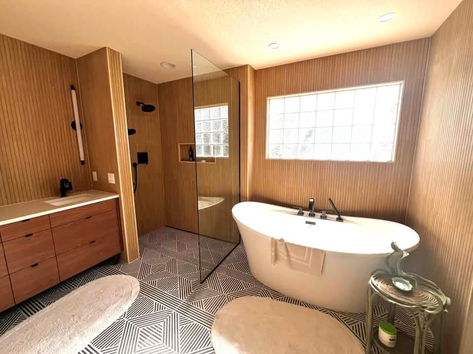 Luxury master bathroom remodel in Fort Collins, Colorado featuring a freestanding soaking tub, glass walk-in shower, and geometric tile floor