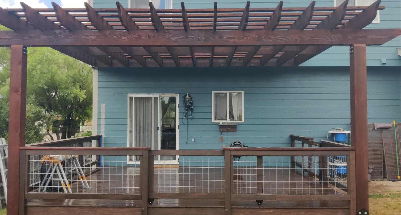 Custom cedar deck with a fan-slat pergola cover and hog-wire panel railing on a home in Loveland, Colorado
