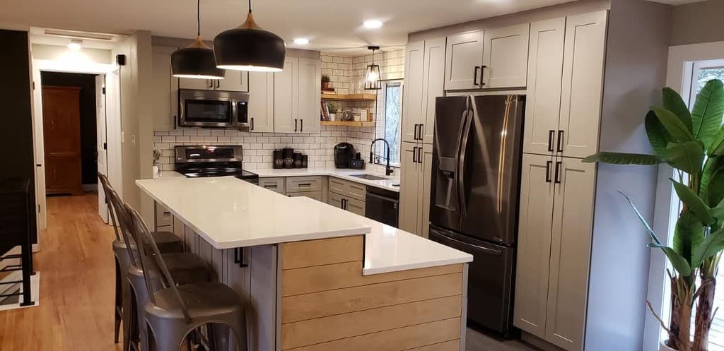 Finished kitchen remodel in Fort Collins with a quartz waterfall island, custom grey shaker cabinets, and modern pendant lighting