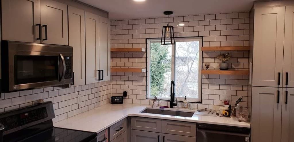 Subway tile backsplash with custom floating wood shelves, a matte black pendant light, and a farmhouse sink in a Fort Collins kitchen remodel